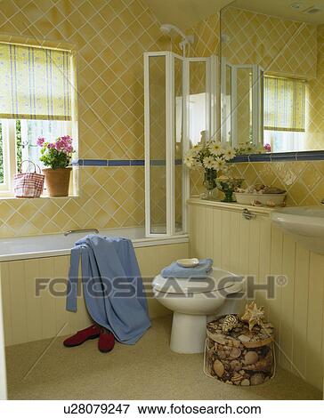 Stock Photo - Folding glass shower doors on bath in traditional bathroom with cream wall tiles. Fotosearch