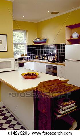 Freestanding wooden bookshelves beside peninsular unit with melamine worktop in modern yellow kitchen View Large Photo Image Stock Photography - Freestanding wooden bookshelves beside peninsular unit with melamine worktop in modern yellow kitchen. Fotosearch