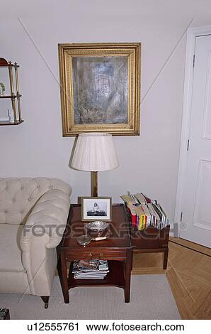 Gilt-framed picture above small table beside cream sofa in apartment living room View Large Photo Image Stock Image - Gilt-framed picture above small table beside cream sofa in apartment living room. Fotosearch