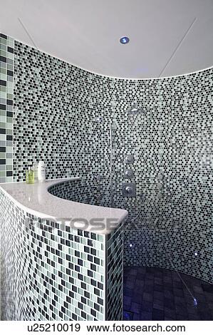 Stock Photo - Glass mosaic tiles on curved walls of shower with body jets. Fotosearch