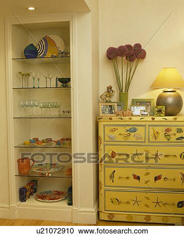 Glass shelves in alcove beside painted yellow chest-of-drawers View Large Photo Image Stock Image - Glass shelves in alcove beside painted yellow chest-of-drawers. Fotosearch