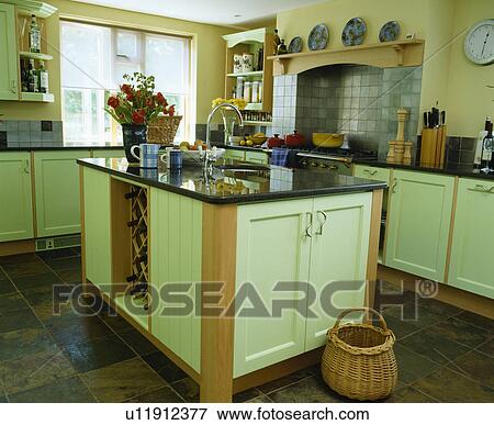 Granite topped island unit in country kitchen with pale green fitted units View Large Photo Image Stock Photo - Granite topped island unit in country kitchen with pale green fitted units. Fotosearch