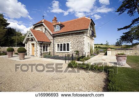 Stock Image - Gravel drive in front of stone country house. Fotosearch