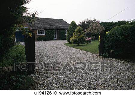 Stock Image - Gravel drive through formal garden to bungalow. Fotosearch
