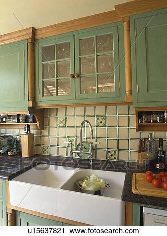 Green fitted cupboard with glazed doors above double white ceramic sink View Large Photo Image Stock Image - Green fitted cupboard with glazed doors above double white ceramic sink. Fotosearch