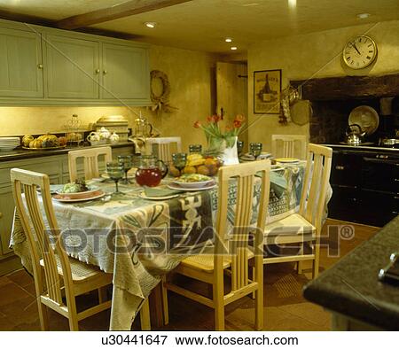 Green glasses and patterned cloth on table in country kitchen with green fitted units View Large Photo Image Stock Photo - Green glasses and patterned cloth on table in country kitchen with green fitted units. Fotosearch