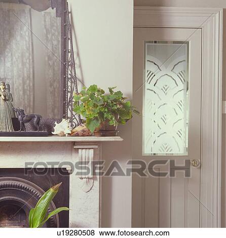 Green houseplant on mantelpiece beside door with engraved glass panel View Large Photo Image Stock Photo - Green houseplant on mantelpiece beside door with engraved glass panel. Fotosearch