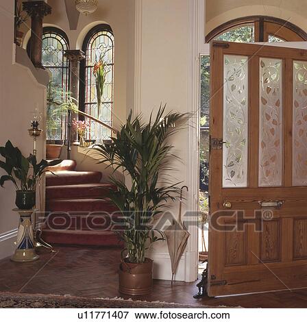 Green houseplants beside staircase and front door in traditional hall View Large Photo Image Stock Photo - Green houseplants beside staircase and front door in traditional hall. Fotosearch