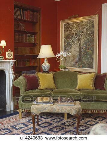 Green velour sofa and tapestry stool in front of lighted painting in corner of red country living room View Large Photo Image Stock Image - Green velour sofa and tapestry stool in front of lighted painting in corner of red country living room. Fotosearch