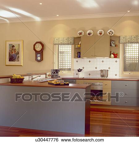 Stock Photograph - Grey fitted units in modern kitchen with downlighting. Fotosearch