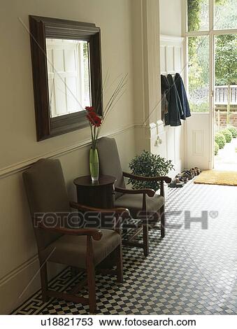 Grey upholstered chairs below large mirror in hall with chequerboard floor tiles View Large Photo Image Stock Image - Grey upholstered chairs below large mirror in hall with chequerboard floor tiles. Fotosearch