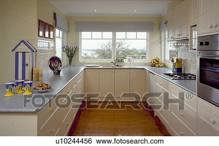 Stock Photograph - Grey worktops on cream units in compact kitchen. Fotosearch