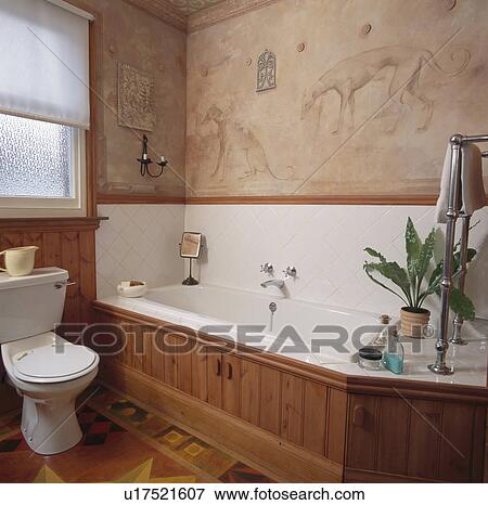 Stock Photo - Handpainted mural above wooden panelled bath in traditional bathroom. Fotosearch