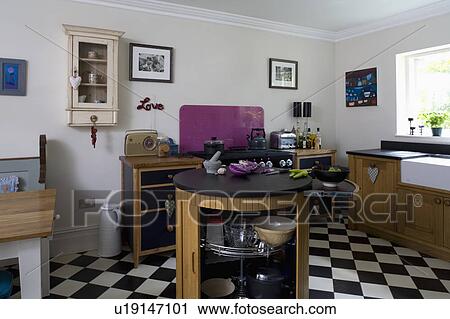 Island unit with black granite worktop and tambour door in white kitchen with black+white chequerboard flooring View Large Photo Image Stock Image - Island unit with black granite worktop and tambour door in white kitchen with black+white chequerboard flooring. Fotosearch