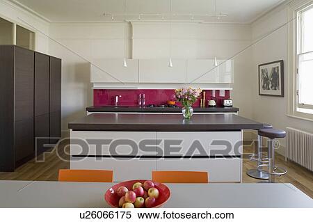 Stock Photography - Island unit with cast concrete resin worktop in modern kitchen with white gloss lacquer units. Fotosearch
