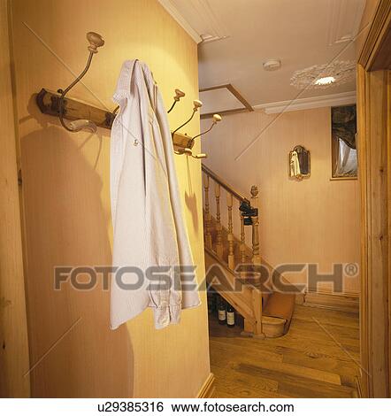 Stock Photograph - Jacket on wall-hooks in traditional yellow hall with wooden flooring. Fotosearch