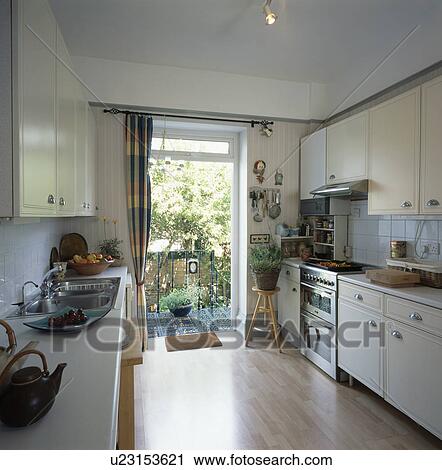 Laminated wood flooring in white economy-style kitchen with door open to balcony View Large Photo Image Stock Image - Laminated wood flooring in white economy-style kitchen with door open to balcony. Fotosearch