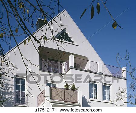 Stock Image - Large and small balconies on modern white house with apex roof. Fotosearch