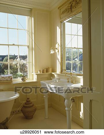 Large antique gilt mirror above white basin in cream bathroom with sash window View Large Photo Image Stock Image - Large antique gilt mirror above white basin in cream bathroom with sash window. Fotosearch