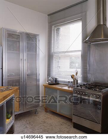 Stock Photography - Large metal cupboard with opaque glass doors in modern kitchen with range oven. Fotosearch