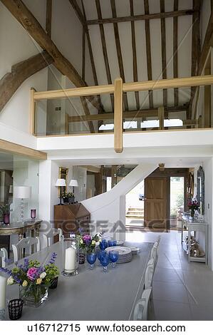 Stock Photography - Large open-plan dining room with gallery landing in country barn conversion. Fotosearch