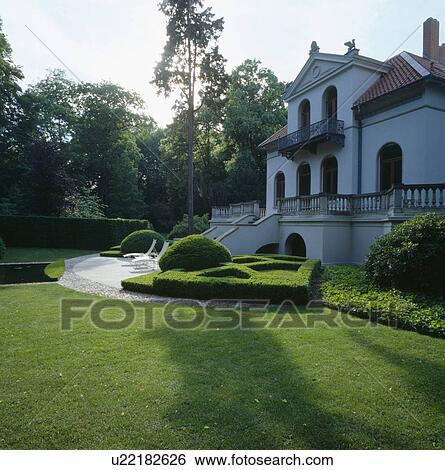 Lawn and clipped box parterre in front of traditional white country house View Large Photo Image Stock Photograph - Lawn and clipped box parterre in front of traditional white country house . Fotosearch