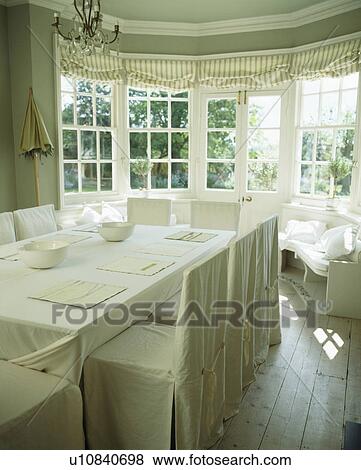 Linen loosecovers on chairs in cream country dining room with linen tablecloth View Large Photo Image Stock Photo - Linen loosecovers on chairs in cream country dining room with linen tablecloth. Fotosearch