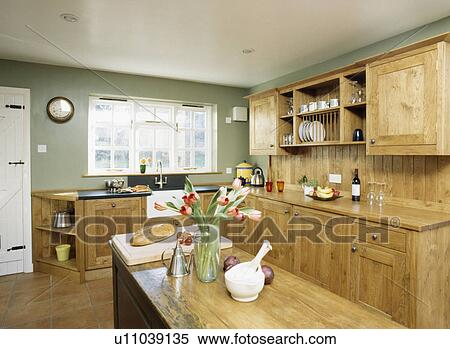 Stock Photography - Long island unit in grey country kitchen with fitted wooden units. Fotosearch
