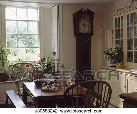 Longcase clock in small country dining room with Windsor chairs and wooden table View Large Photo Image Stock Image - Longcase clock in small country dining room with Windsor chairs and wooden table. Fotosearch