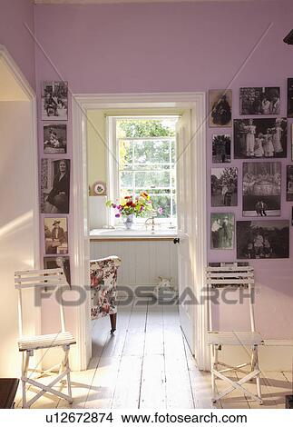 Picture - Looking through to the bathroom from the landing with white painted floorboards and collection of black and white photographs around the doorway.. Fotosearch