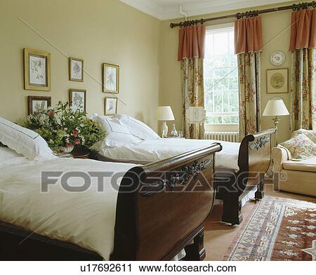Stock Image - Mahogany twin beds in country bedroom. Fotosearch
