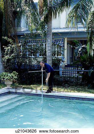 Man using net to clean swimming pool View Large Photo Image Stock Photograph - Man using net to clean swimming pool. Fotosearch