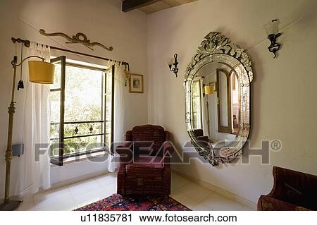 Stock Image - Maroon armchair and large Venetian mirror in dressingroom with white curtains. Fotosearch
