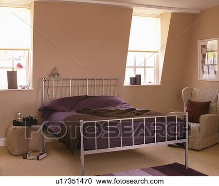 Stock Image - Metal bed with purple linen in modern loft conversion bedroom. Fotosearch