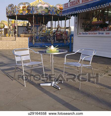 Metal chairs and small metal table on paving outside seaside cafe View Large Photo Image Stock Photo - Metal chairs and small metal table on paving outside seaside cafe. Fotosearch