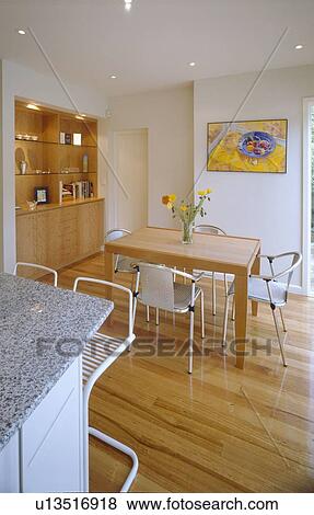 Stock Photo - Metal chairs and wooden table in modern dining room with wooden flooring and recessed ceiling lighting. Fotosearch