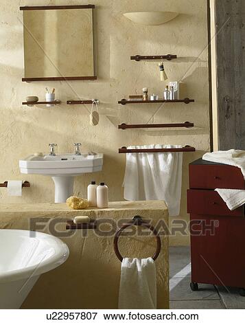 Stock Photo - Mirror and small wooden shelves on rough stone wall in neutral bathroom. Fotosearch