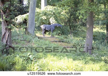 Stock Photograph - Modern horse sculpture in woodland garden. Fotosearch