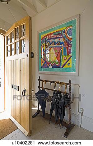 Modern painting on wall above antique umbrella storage rack in hall with Arts+Crafts front door View Large Photo Image Stock Image - Modern painting on wall above antique umbrella storage rack in hall with Arts+Crafts front door. Fotosearch