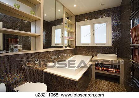 Stock Photography - Modern rectangular bath and brown mosaic wall tiles in modern bathroom. Fotosearch