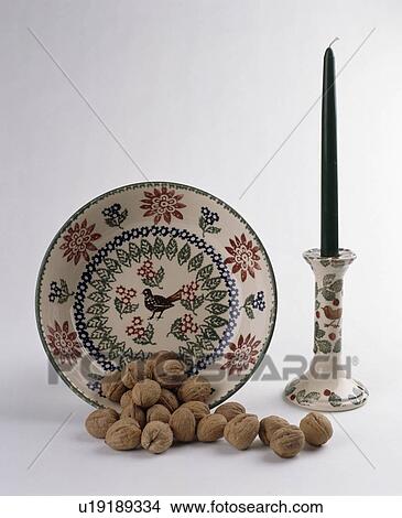 Picture - Naive-print ceramic plate and matching candlestick with pile of walnuts. Fotosearch