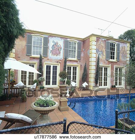 Neo-classical mural painted on wall of large house with swimming pool and tall conifers in planters View Large Photo Image Stock Photograph - Neo-classical mural painted on wall of large house with swimming pool and tall conifers in planters . Fotosearch
