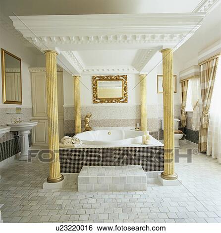 Stock Photograph - Neo-classical-style bathroom with marble pillars at the corners of the bath. Fotosearch