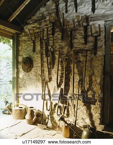 Stock Photo - Old gardening tools on inside stone wall of large porch. Fotosearch