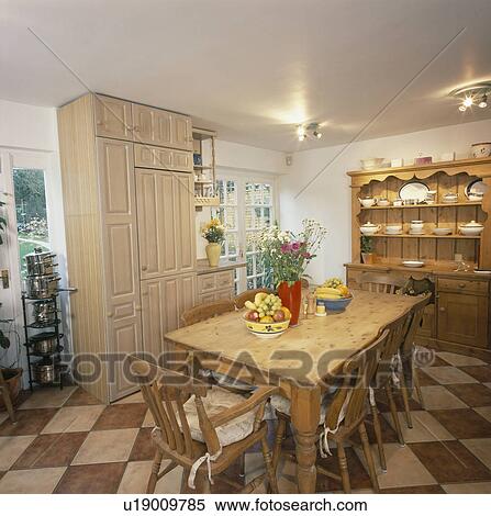 Old pine table and chairs in country kitchen with brown+cream chequerboard flooring View Large Photo Image Stock Photography - Old pine table and chairs in country kitchen with brown+cream chequerboard flooring. Fotosearch