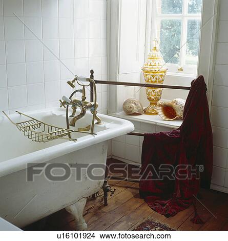 Old roll-top bath with brass taps and shower-head in traditional white tiled country bathroom View Large Photo Image Picture - Old roll-top bath with brass taps and shower-head in traditional white tiled country bathroom. Fotosearch