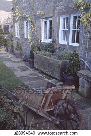 Old wooden wheelbarrow besidepath in front of traditional stone country house View Large Photo Image Stock Photo - Old wooden wheelbarrow besidepath in front of traditional stone country house. Fotosearch