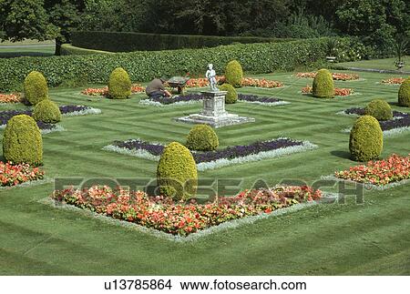 Orange begonias and small clipped conifers in large formal garden with mown grass paths and man weeding View Large Photo Image Picture - Orange begonias and small clipped conifers in large formal garden with mown grass paths and man weeding. Fotosearch