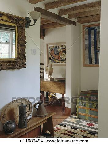 Ornate mirror above wooden bench with old pewter jugs in small cottage hall with ikat rug View Large Photo Image Picture - Ornate mirror above wooden bench with old pewter jugs in small cottage hall with ikat rug. Fotosearch