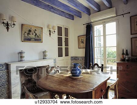 Painted blue ceiling beams in Mediterranean dining room with wooden table and chairs and French windows View Large Photo Image Picture - Painted blue ceiling beams in Mediterranean dining room with wooden table and chairs and French windows. Fotosearch